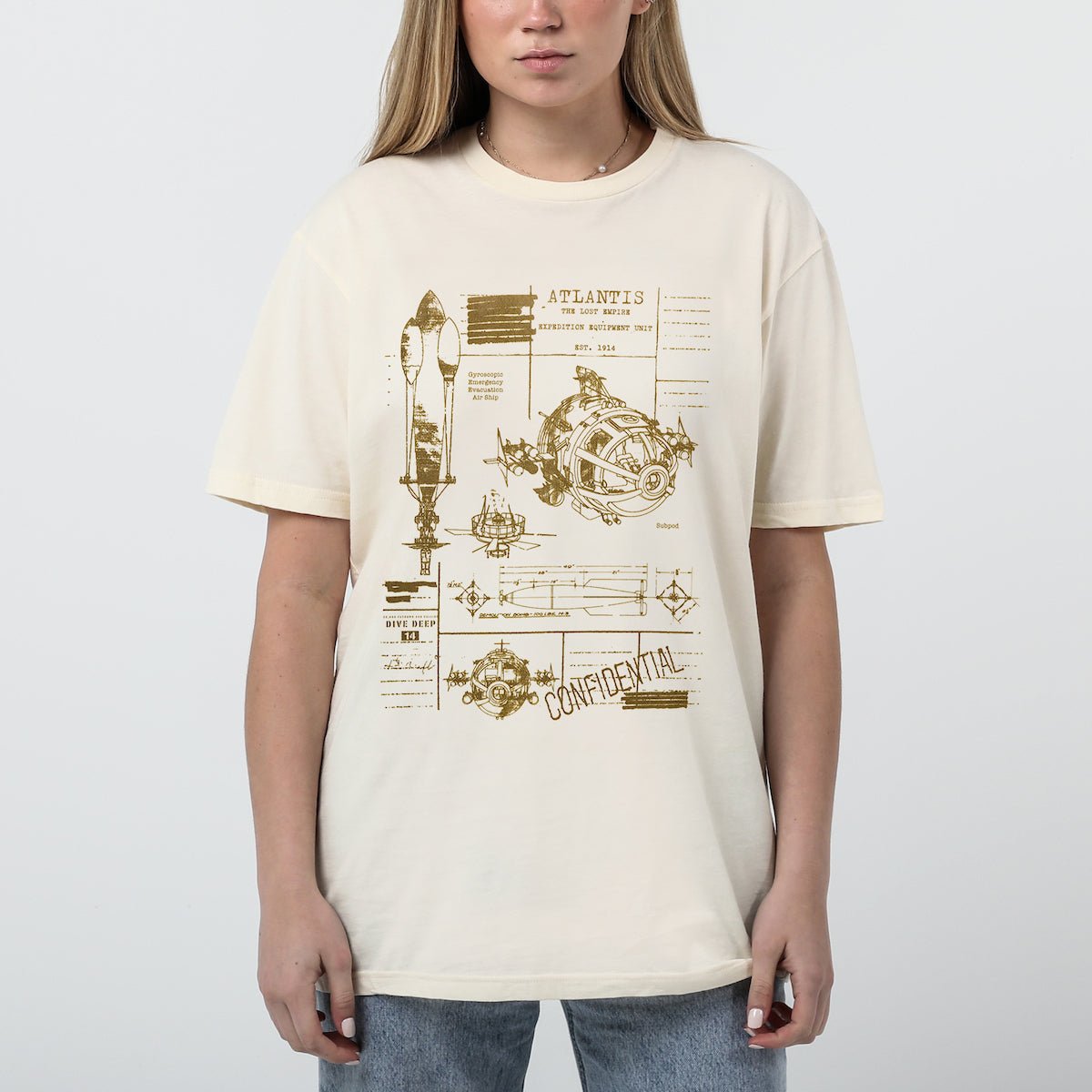 Woman in a beige tee with Blueprint-style illustration of vehicles and diagrams for an Atlantis expedition.