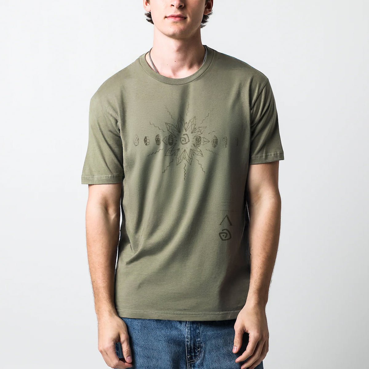 Man in a green T-shirt with a dark blue abstract sunburst design and text in the bottom right corner.