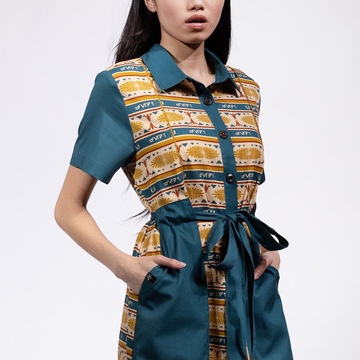 A woman in a button up yellow and teal dress thats star wars jedi inspired with a striped tapestry pattern