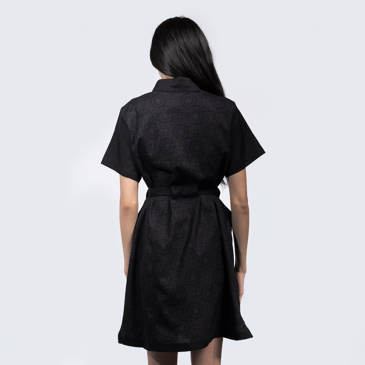 A woman standing backwards in a black dress thats star wars imperial inspired with a geometric pattern