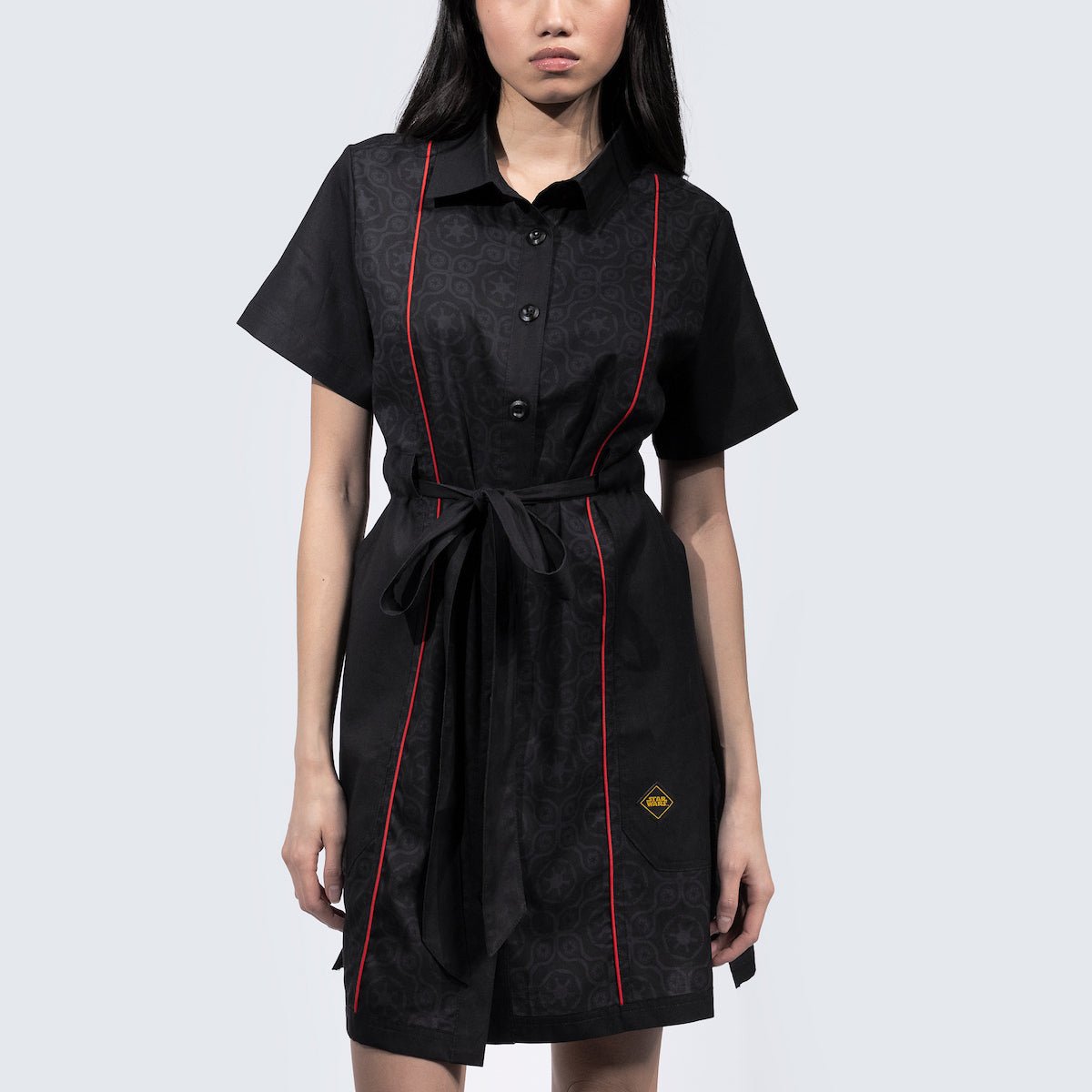 Women in a button up black dress thats star wars imperial inspired with a geometric pattern and red details