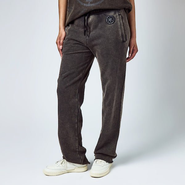 Woman in black sweatpants with an elastic waistband and black drawstring, featuring a small black Empire logo near the left pocket and a vertical "Empire" graphic printed in distressed black text along the lower left leg.