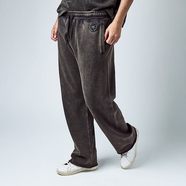 Man in black sweatpants with an elastic waistband and black drawstring, featuring a small black Empire logo near the left pocket and a vertical "Empire" graphic printed in distressed black text along the lower left leg.