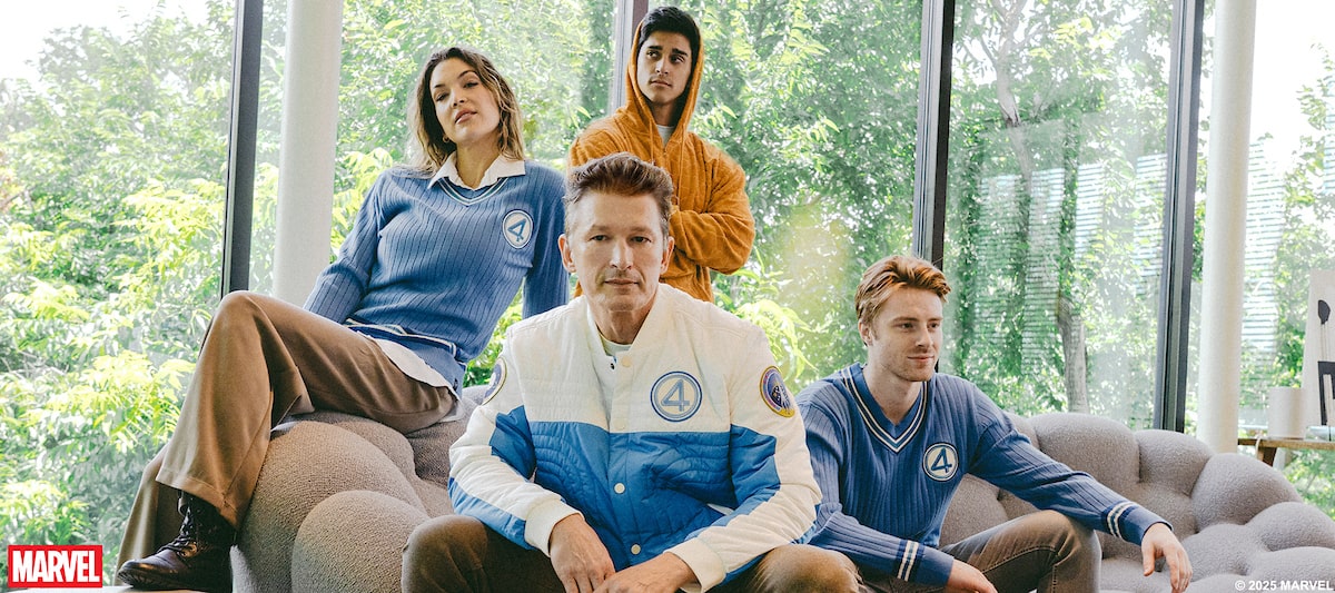Four people sitting on a couch in a modern living room with large windows.