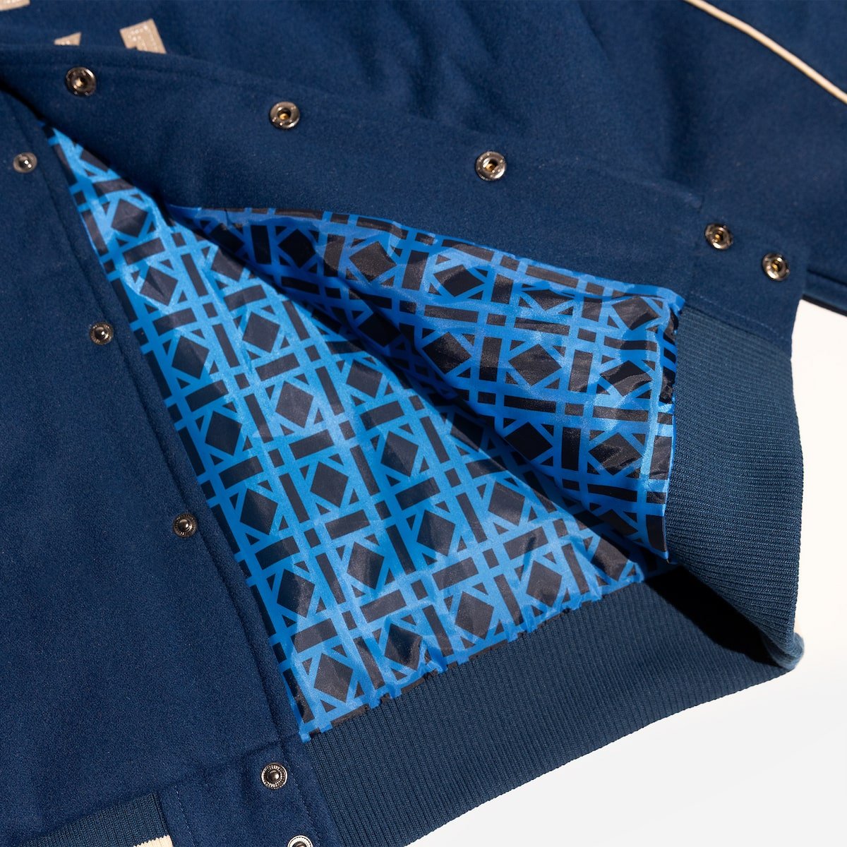 Close-up of a blue jacket with geometric patterned lining on a white background