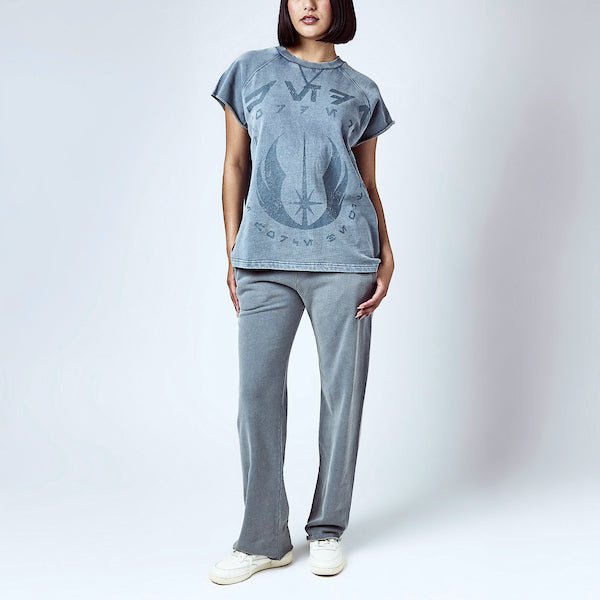 A woman dressed in a blue sleeveless crew neck and blue wide leg sweatpants, featuring a Star Wars Jedi themed lounge set