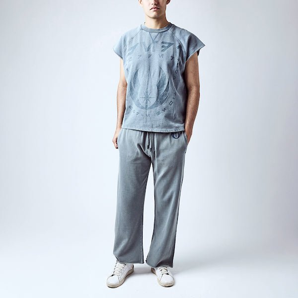 A man dressed in a blue sleeveless crew neck and blue wide leg sweatpants, featuring a Star Wars Jedi themed lounge set