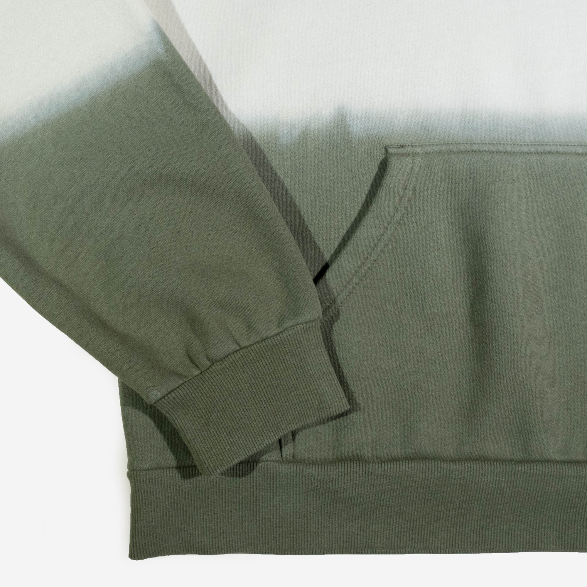 A dip-dyed hoodie in cream and green featuring X-Men's Rogue and Gambit. The front displays a small X-Men logo, while the back showcases a black-and-white comic-style illustration of Rogue and Gambit embracing, with the word "Sugah" below.