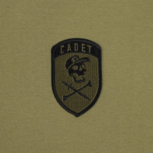 The photo shows up-close detail of the patch on the green hoodie. The patch is military style with the word "Cadet" at the top and a Skull and cross bones underneath. The Skull is wearing a hat!