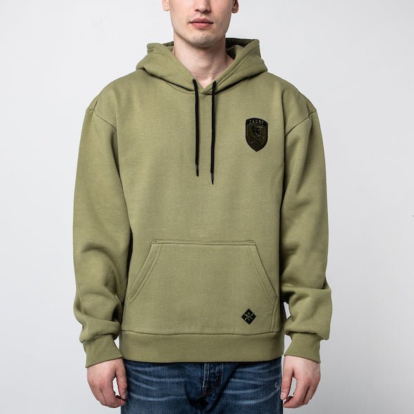 The photo is of a man in a Green Hoodie with Kangaroo Pocket and Hood. The Hoodie has a patch on the right chest area and black strings to tighten the hood