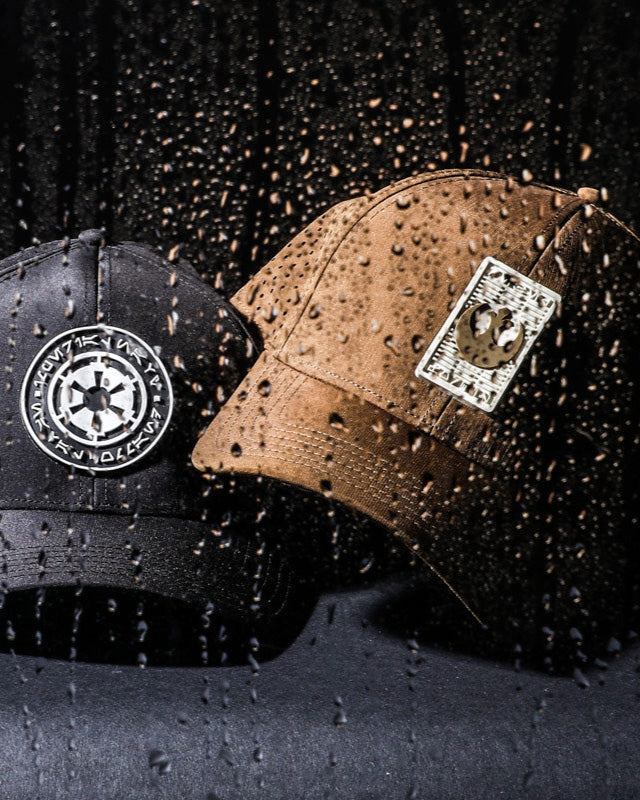 Two baseball caps with logos on a dark textured background