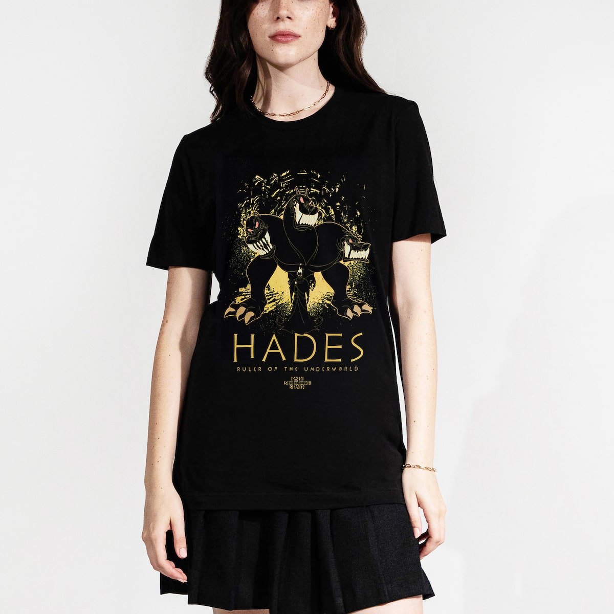 Woman in a black tee with an Illustration of a three-headed dog with a shadowy figure, hades, in front of it, set against an abstract background.
