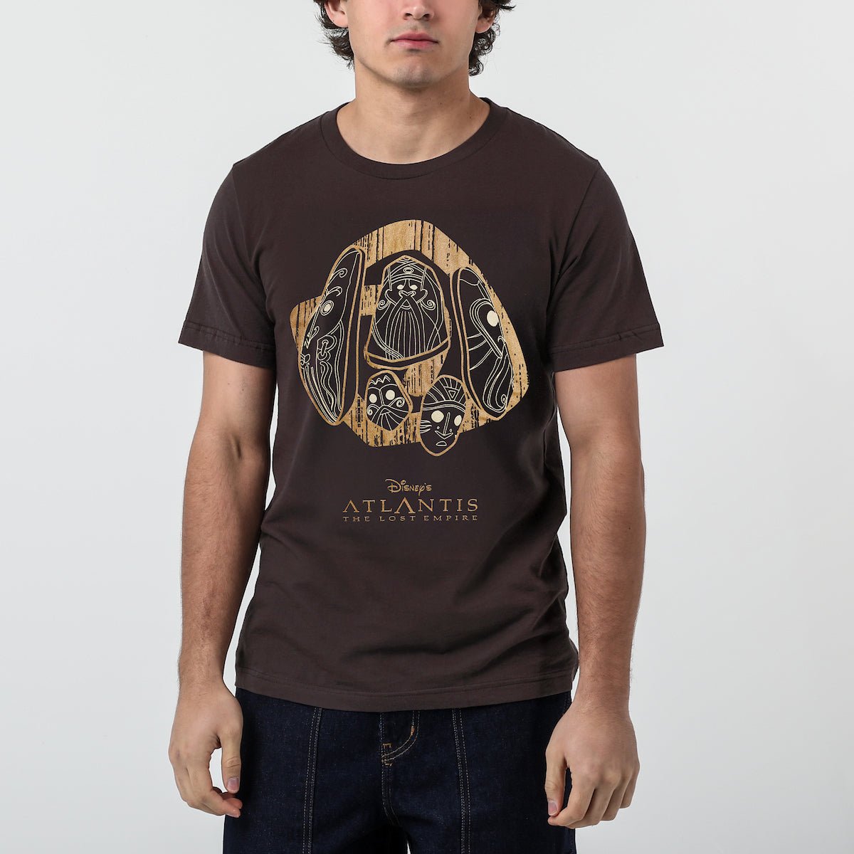 Man in a brown tshirt with stylized stone carvings with intricate designs on a dark background, with the text "Disney's Atlantis The Lost Empire" below.