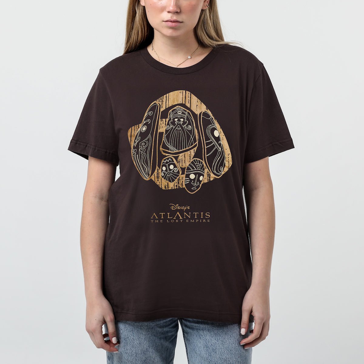 Woman in a brown tshirt with stylized stone carvings with intricate designs on a dark background, with the text "Disney's Atlantis The Lost Empire" below.