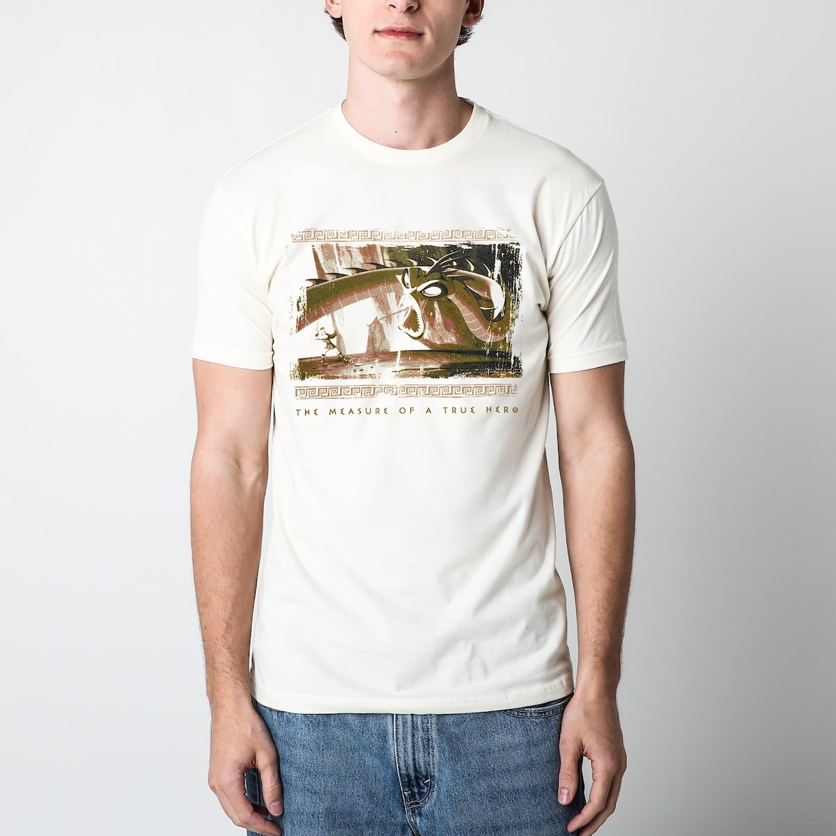 Man in a beige tshirt with an Illustration of Hercules facing a Hydra with the text "THE MEASURE OF A TRUE HERO" below