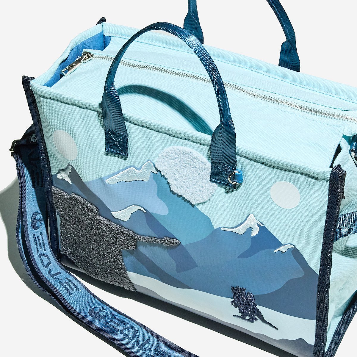 Light blue bag with mountain design on a white background