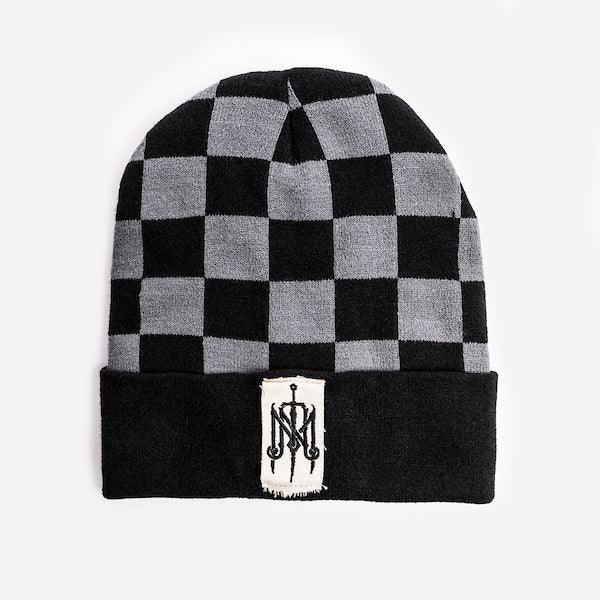 A beanie featuring a black and gray checkered pattern across the top. The folded cuff is solid black with a rectangular white patch in the center, displaying an ornate embroidered monogram logo in black. The patch has slightly frayed edges for a rugged, vintage look.