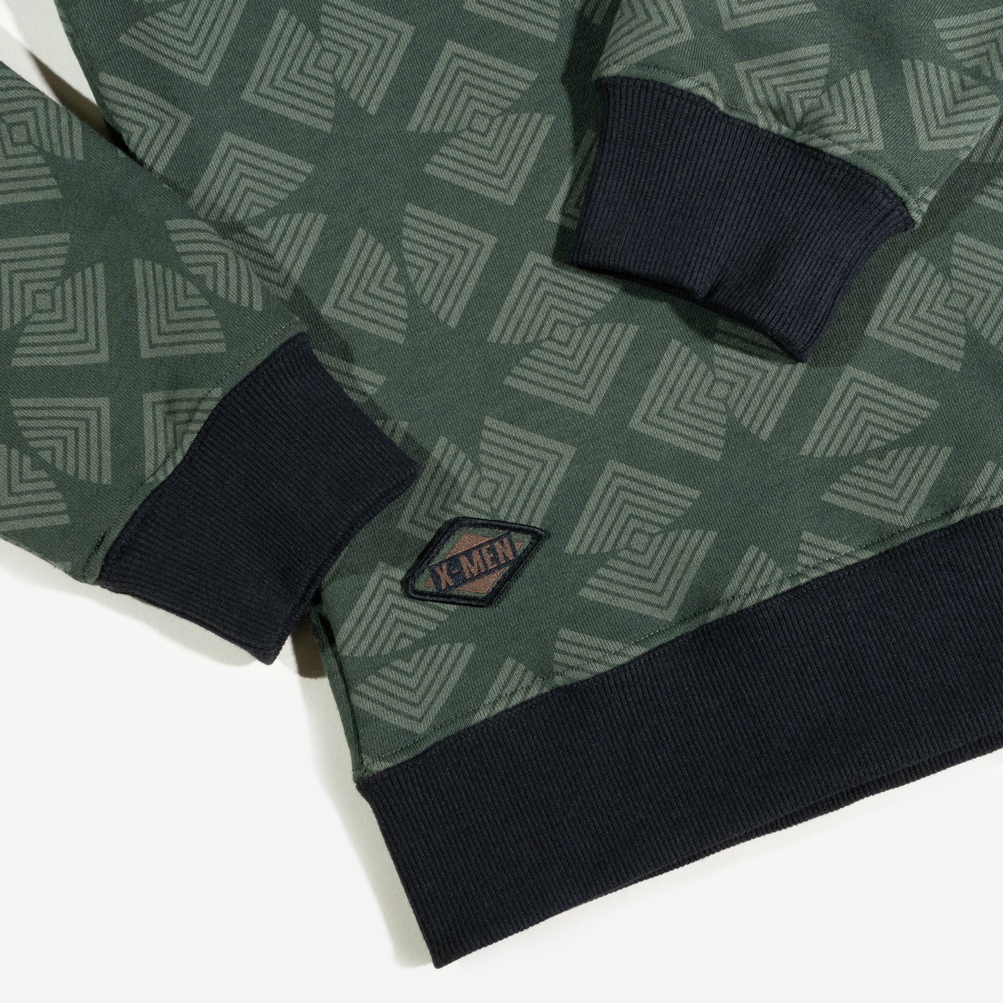 close up of X-Men patch on green X-Men Rogue Crew Sweatshirt featuring an intricate geometric pattern, black ribbed cuffs and hem