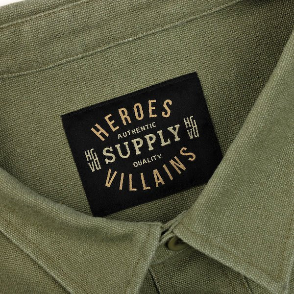 The photo shows a close up of a green shirt jackets label. The label says "Heroes Villains, Authentic Supply Quality"