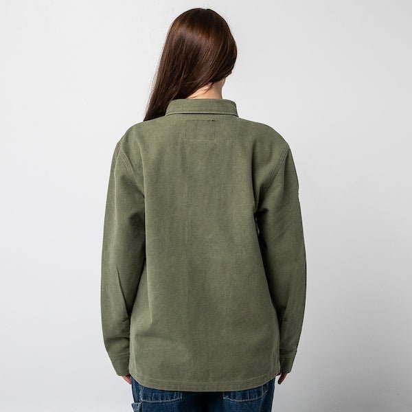 The photo shows a woman standing backwards to show the back of a green military style shirt jacket.
