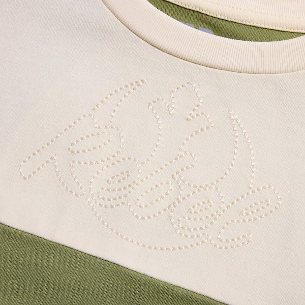 a close up of the top cream panel showing a single stitch embroidery that says "Rebel" with the rebel emblem behind the word.