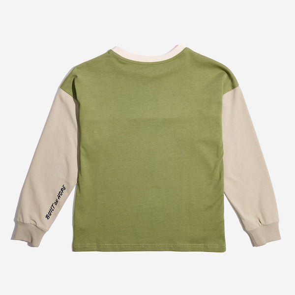 The back of a color blocked long sleeve shirt. The sleeves are a tan color while the collar is cream colored and the remainder is green. There is an embroidery on the left sleeve that reads "Built on hope"