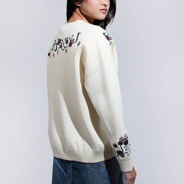 Woman facing backwards in a White Cardigan featuring embroidered Cherry Blossoms across the top of the back