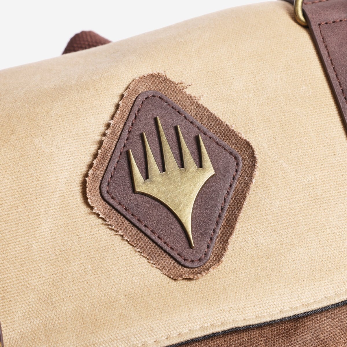 Beige bag with a brown patch featuring a gold MTG emblem on a white background