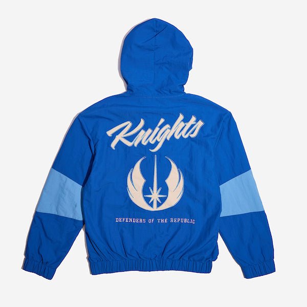 The back of a Star Wars-themed hooded windbreaker jacket, primarily blue with light blue and cream colored accents. The design features large, bold text reading 'Knights' across the upper back, with the Jedi Knight emblem in white with a blue boarder it. Beneath the emblem, the words 'Defenders of the Republic' are printed in a smaller font. The jacket has an elastic waistband and cuffs, with a color-blocked pattern matching the front design.