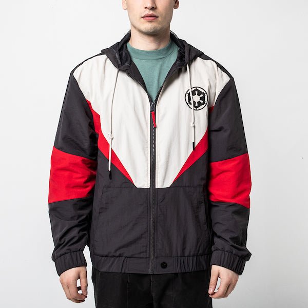 A man in a Star Wars-themed hooded windbreaker jacket featuring a Imperial Army emblem on the left chest. The jacket has a color-blocked design in Black, White and Red, with a front zipper, adjustable drawstrings on the hood, elastic cuffs, and two zippered pockets.