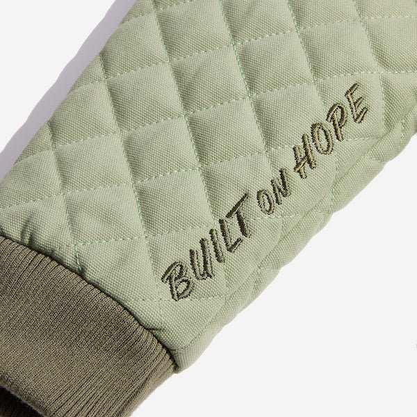 A close up of the left sleeve showing an embroidery near the wrist cuff that says "Built on Hope"