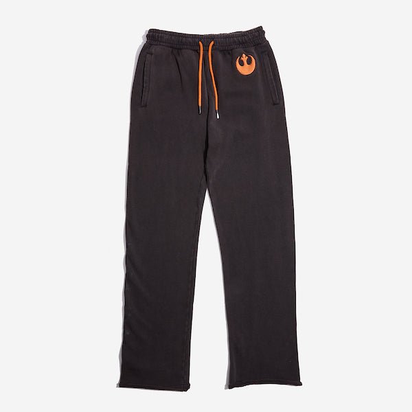 Dark Grey sweatpants with an elastic waistband and orange drawstring, featuring a small orange rebel logo near the left pocket and a vertical "Rebel" graphic printed in distressed black text along the lower left leg.