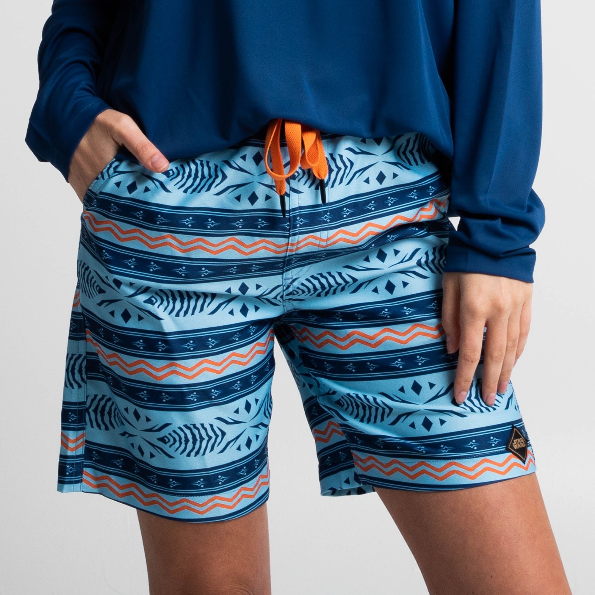 Ahsoka Board Shorts with all-over blue and orange tribal print, drawstring waist, side and back pockets, quick-dry fabric.