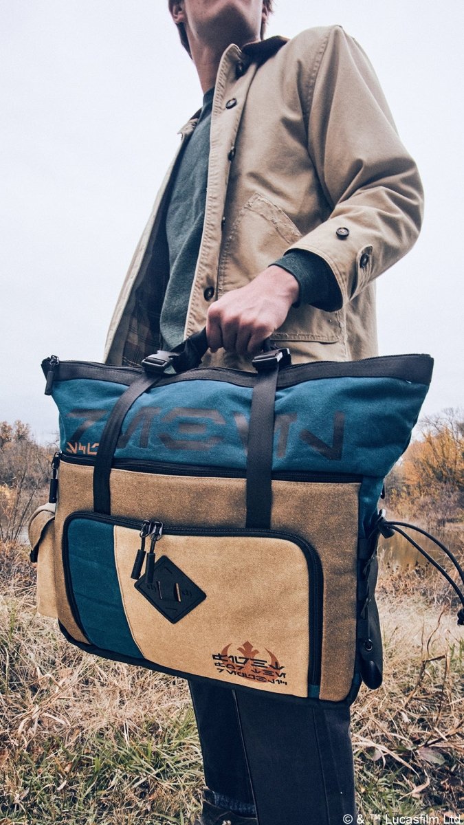 Man carrying the Heroes & Villains Rebel Teal Commuter Bag in a nature scene.
