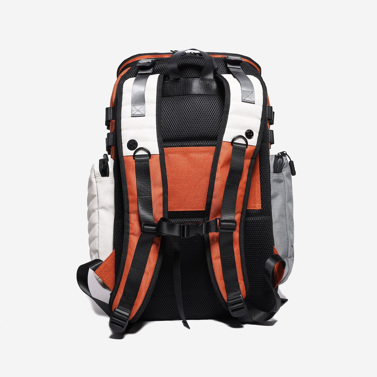 Multicolored backpack with orange, black, and white sections on a light gray background