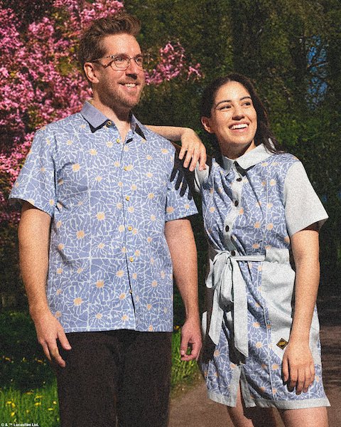 Couples standing in a park wearing a star wars themed rebel button up shirt and matching button up dress