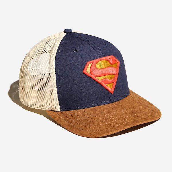 A photo of a trucker hat. It has a white mesh back, a brown suede bill and the front is blue dawning the S-Shield from Supermans uniform