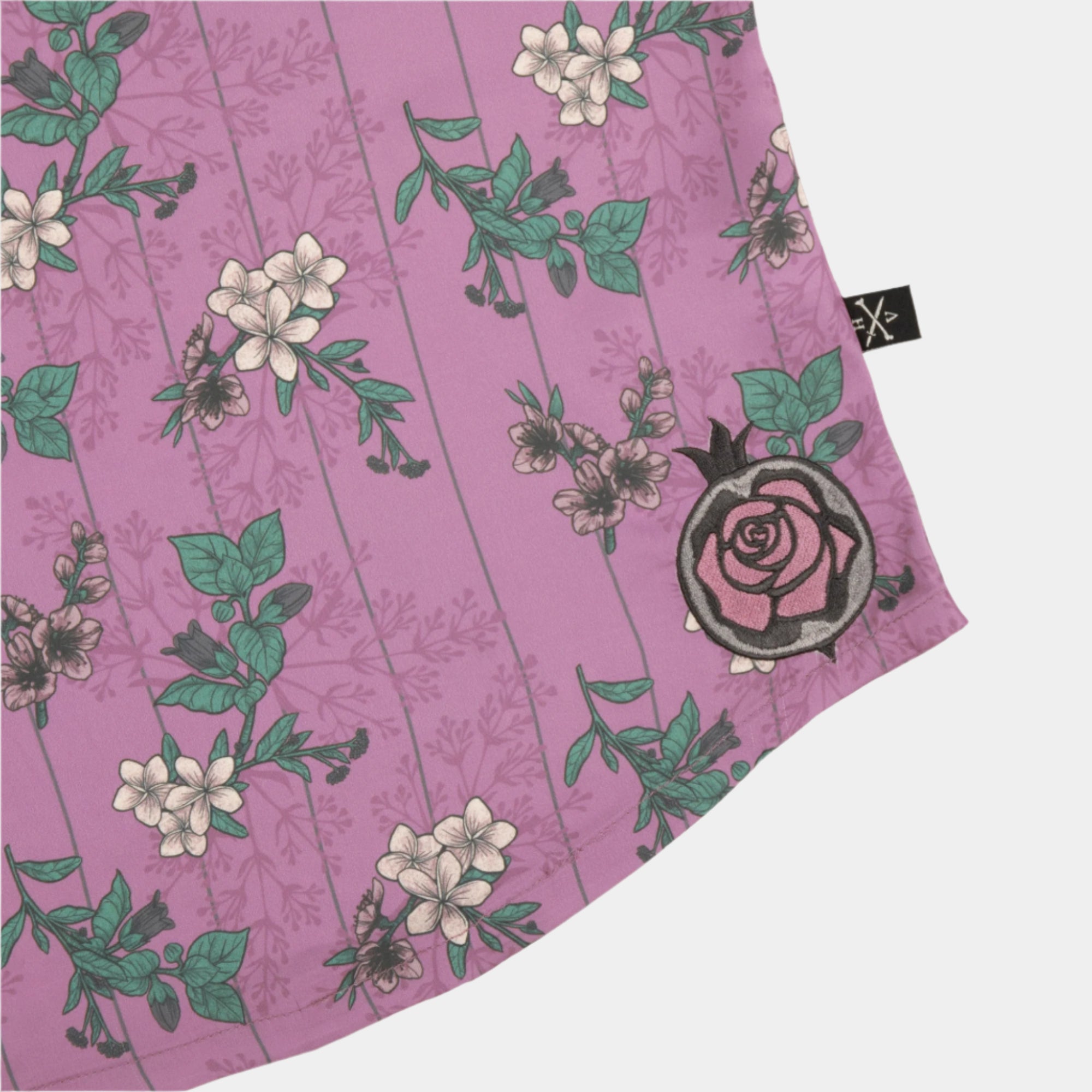 Close-up of the embroidered rose on the front of the Lore Olympus Goddess of Spring Satin Cami in pink with an all-over floral print.