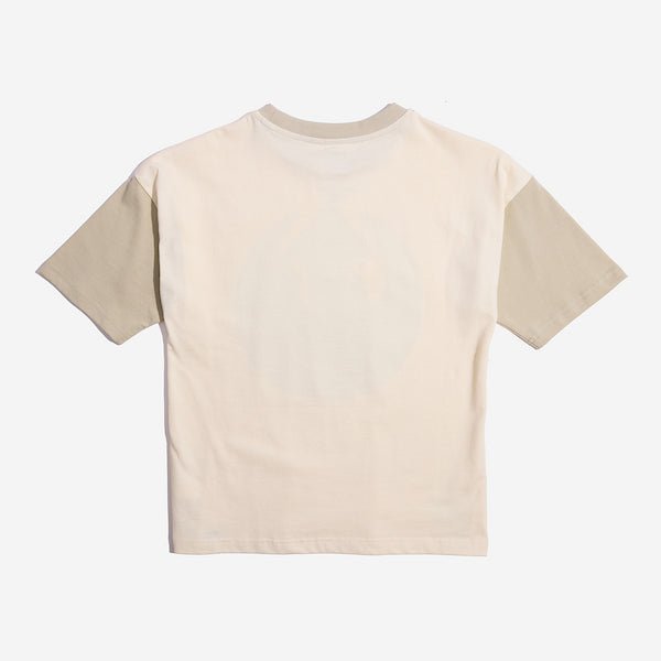The photo shows the back of a color blocked tshirt. The sleeves and collar are a tan color while the remainder of the tshirt is a cream color.