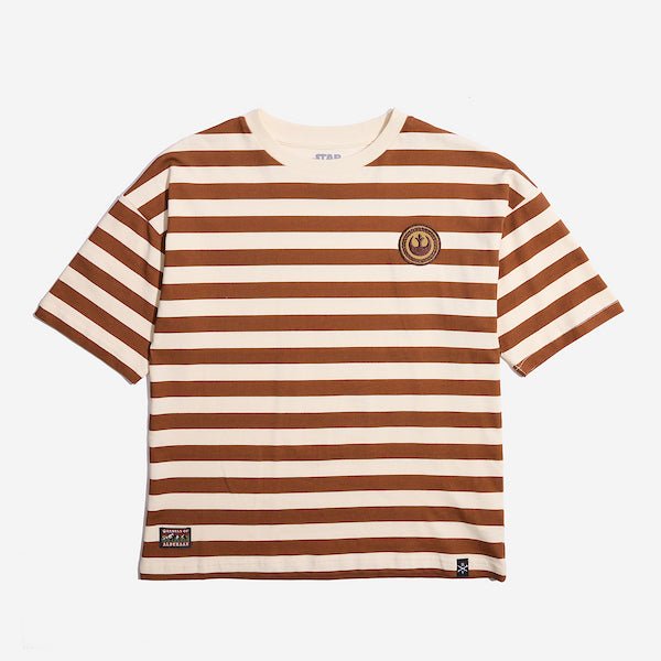 Photo shows a t-shirt with white and orange horizontal stripes. There is a circular patch on the right chest with the Star Wars Rebel emblem. The emblem is within a braided circle that represents princess leias iconic braids. The bottom right of the t-shirt has a rectangular patch with the words "Rebels of" at the top and "Alderaan" at the bottom. Between the words is a small picture of a forest and mountains.