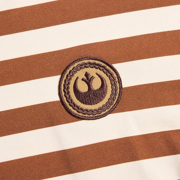 Photo shows a close up of a t-shirt with white and orange horizontal stripes. There is a circular patch with the Star Wars Rebel emblem. The emblem is within a braided circle that represents princess leias iconic braids.