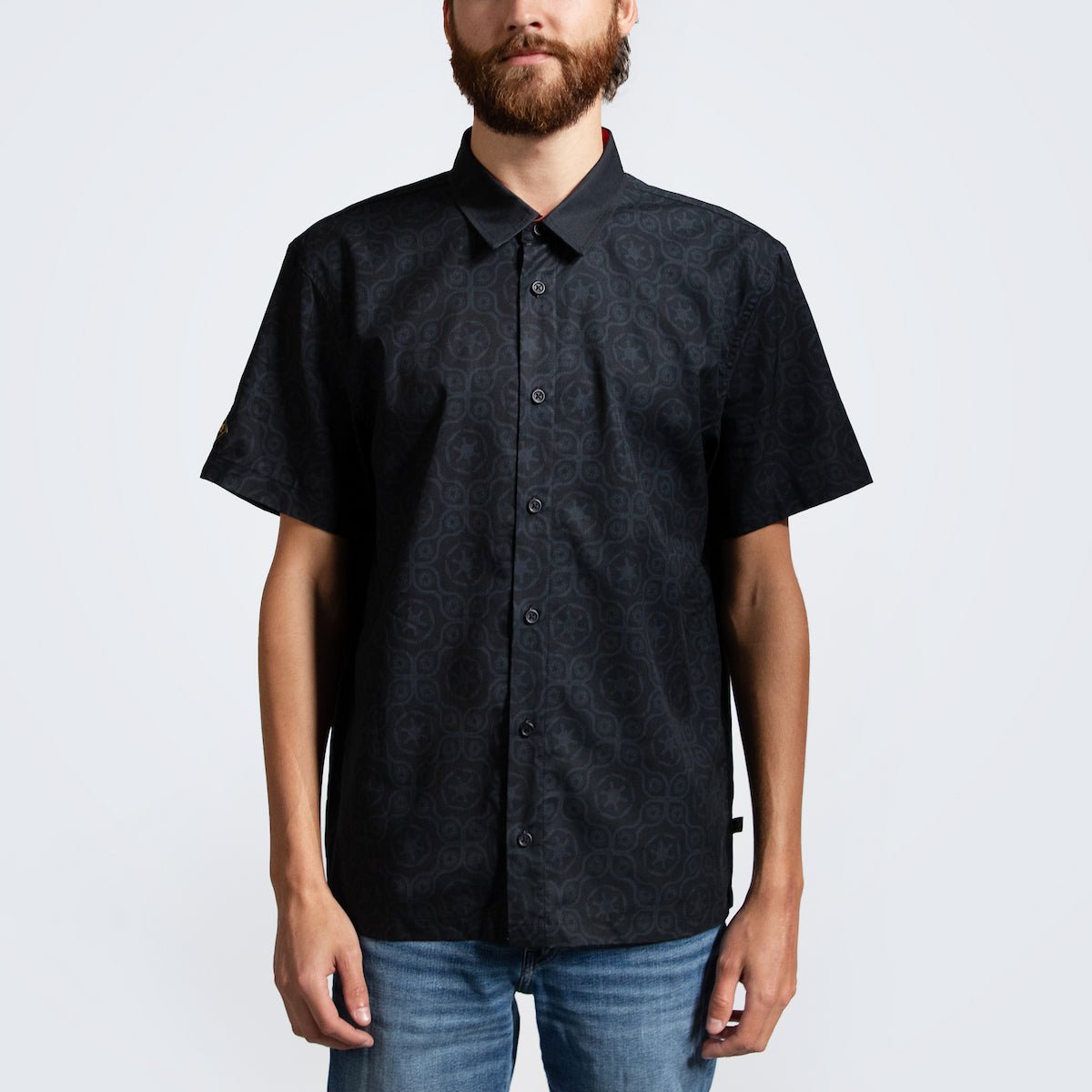 A man in a button up black shirt with red details in a star wars imperial geometric pattern