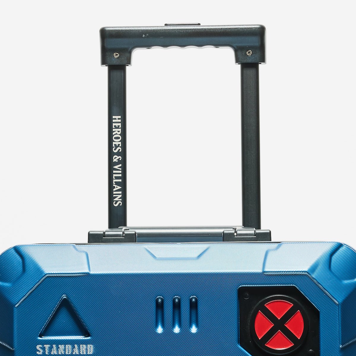 Blue suitcase with 'Heroes & Villains' branding on the handle against a white background