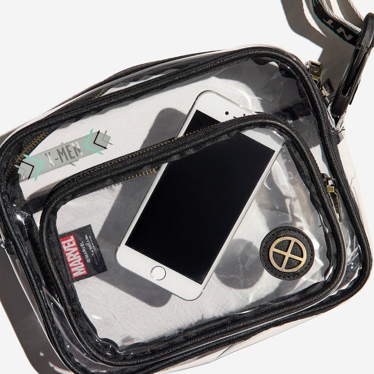Clear bag with black zipper containing a smartphone, Marvel X-Men branded item, and other small objects on a white background.