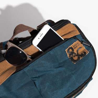 Blue bag with sunglasses and phone, featuring a Dungeons & Dragons logo on a light gray background