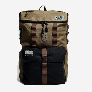 Brown and black backpack with Mandalorian and Grogu Theme. The Bag has a metal "Mudhorn" emblem in the center and a smaller grogu graphic on the front pocket. The back sits on a white background