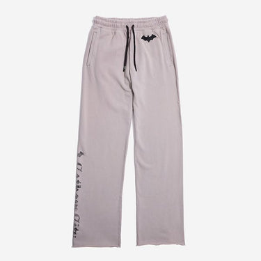 Light gray sweatpants with an elastic waistband and black drawstring, featuring a small black Batman logo near the left pocket and a vertical "Gotham City" graphic printed in distressed black text along the lower left leg.