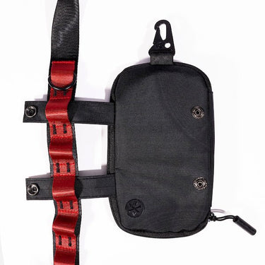 The photo shows a close up detailing of the shoulder strap. Featured is the Blue decorative detailing. The detailing has loops for attaching clips and a tech case. The tech case is pictured to the right side displaying the straps going through the loops. The top loop has a "D"-Ring attached.