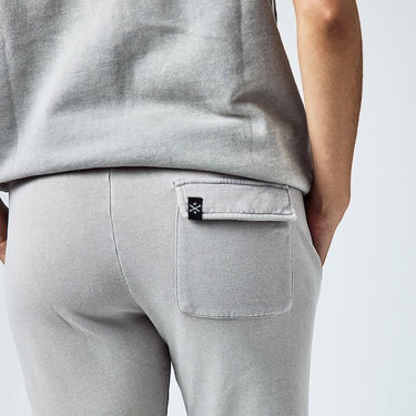 Close up of a person wearing light grey sweatpants with a back pocket 