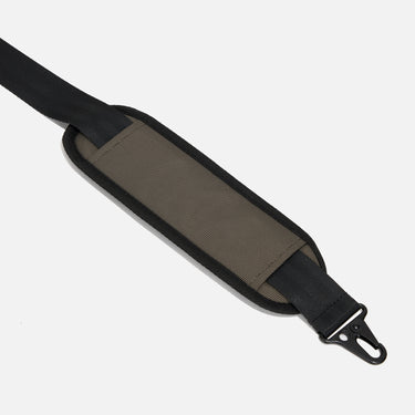 Rugged duffle bag in earthy tones with black straps, blue accent detailing, and a durable design. Features multiple compartments, reinforced handles, and an adjustable shoulder strap for versatile carrying.